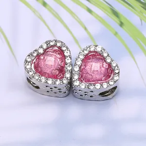 Vue macro de charms cœur en argent avec opale rose et bordure en strass étincelants