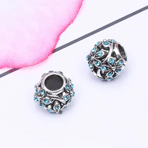Vue macro de perles argentées en forme de fleur avec strass bleus pour bijoux DIY