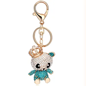 Golden alloy teddy bear keychain with crown and sparkling blue and white rhinestones