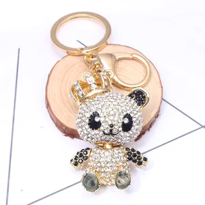 Detailed view of panda keychain with sparkling rhinestones and a gold crown on wood base