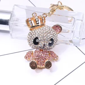 Sparkling panda keychain with golden crown and pink rhinestones on a geometric background