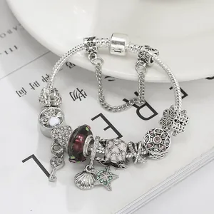Versilbertes Bettelarmband mit Herz-Schlüssel-Anhänger und bunten Perlen auf Magazin
