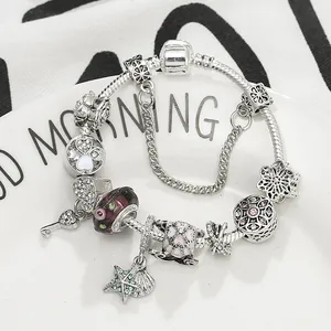 Versilbertes Bettelarmband mit Lavendel-Glasperlen und Herzanhängern auf weißem Teller
