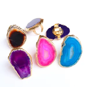 Detalle de anillos ajustables bañados en oro con rodajas de ágata natural en varios colores