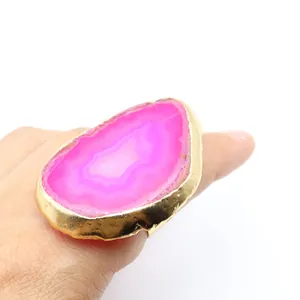 Primer plano de anillo bohemio con rodaja de ágata rosa roja y banda ajustable bañada en oro