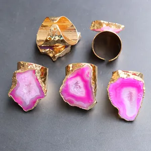 Dettaglio di cinque anelli in agata rosa irregolare con fasce in ottone dorato martellato