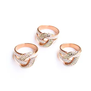 Primer plano de tres anillos entrelazados de oro rosa con pavé de piedras de circón