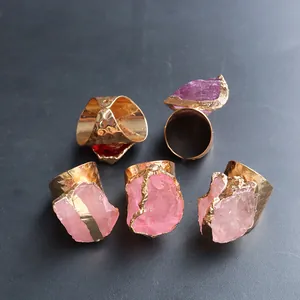Detail view of five raw crystal rings with gold-plated hammered bands on grey background