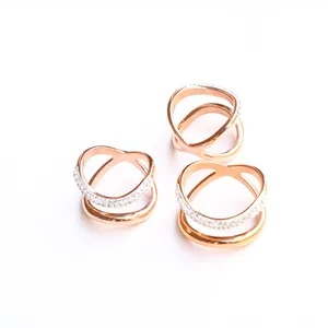 Tres anillos entrelazados en oro rosa con pavé de cristales sobre fondo blanco