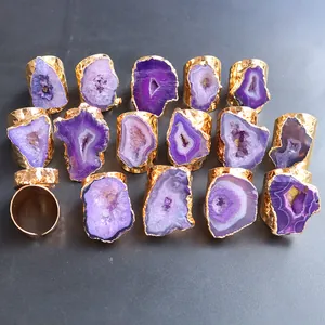 Vista detallada de varias geodas de ágata púrpura natural en anillos dorados ajustables