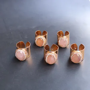 Detalle de anillos dorados martillados con piedras rosas y halos de cristales