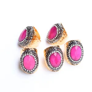 Set of five bohemian gold rings with rose red agate and crystal accents on white background