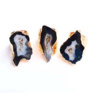 Vista macro di tre fette di geode di agata naturale incastonate in anelli di ottone dorato