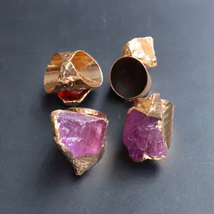 Detailed view of raw purple and red crystal stones on hammered gold plated rings