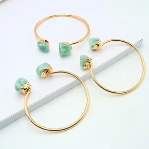 Tre bracciali rigidi placcati in oro con pietre di avventurina verde su fondo bianco