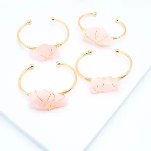 Detailopname van vier handgemaakte rozenkwarts armbanden met gouden draadwikkeling details