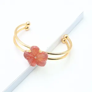 Detailed view of a gold double-row cuff bracelet with a carved pink quartz flower charm