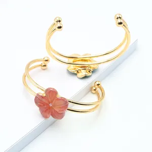 Close-up of dual-band golden bracelets with pink and green quartz stone flower charms