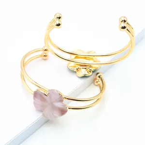 Detail of gold double-band open rings featuring carved quartz flower petals in pink and green