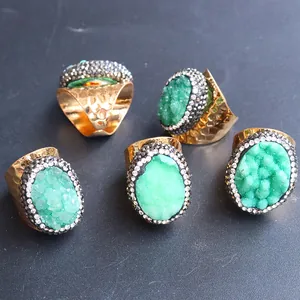 Detail von 5-teiligen goldenen Hammerschlag-Ringen mit ovalen grünen Druzy-Steinen und Kristallen