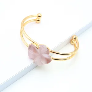 Close-up of gold-plated double-wire cuff bracelet featuring a carved pink quartz flower