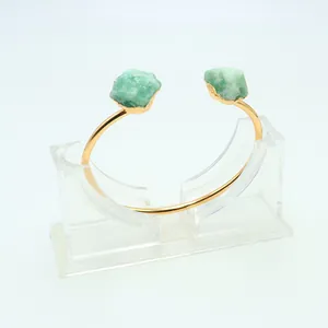 Bracciale rigido dorato aperto con due pietre di avventurina verde grezza su bianco