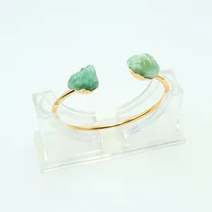 Dettaglio delle pietre grezze di avventurina verde su un bracciale rigido aperto placcato oro