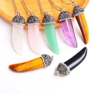 Close-up of horn-shaped natural stone pendants with crystal accents on a wooden tray