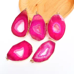Dettaglio di cinque ciondoli in agata rosa con bordi dorati su vassoio di legno