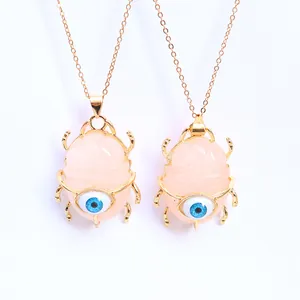 Macro view of gold beetle pendants with pink quartz and blue evil eye detail