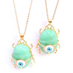Macro shot of beetle pendant with green natural stone and blue evil eye detail