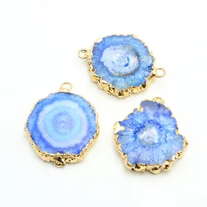 Close-up of blue agate druzy pendants with gold plated edges on a white background