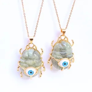 Detail of labradorite beetle pendant with evil eye inlay on a golden metal chain