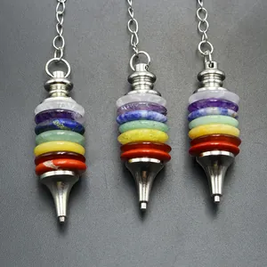 Three 7 Chakra crystal stone pendulum pendants with silver chains on a dark grey background