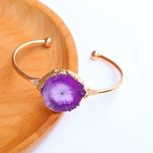 Detalle del brazalete dorado decorado con una gran piedra de ágata druzy púrpura