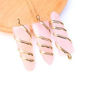 Detail of rose quartz hexagonal prisms with gold wire wrapping on a wooden tray