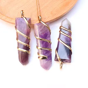 Natural amethyst sword pendant with gold wire wrap on rustic wooden display