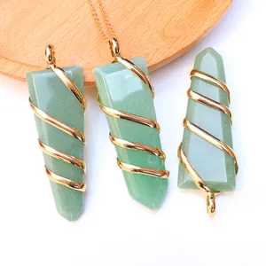 Detail of green natural crystal pendants with golden wire wrap on wood tray