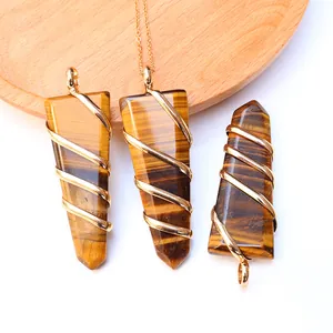 Detailed tiger eye stone sword pendant with intricate gold wire wrapping on wood