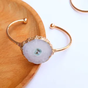 Detalle macro del brazalete de ágata girasol chapado en oro con piedra drusa natural y apertura