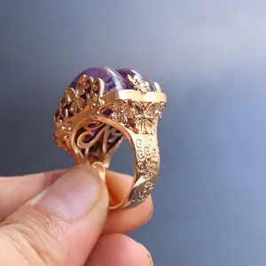 Macro view of rose gold ring showing detailed floral and butterfly carvings with amethysts