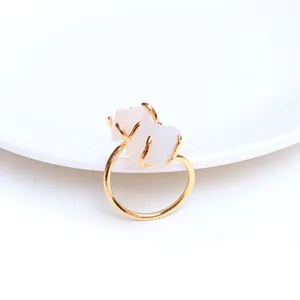 Detail eines vergoldeten Krallenrings mit natürlichen Rosa Kristallen auf weißer Keramik