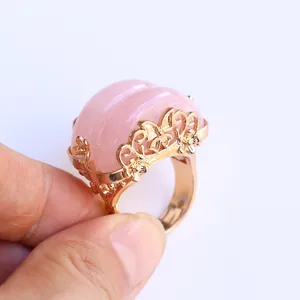 Detail of pink crystal stone on golden ring featuring hollow butterfly and flower design
