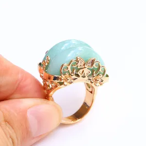 Golden flower and butterfly ring featuring a large light green semi-spherical gemstone