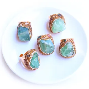 Macro detail of five raw green fluorite rings with pavé crystals on white ceramic plate