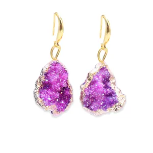 Gros plan sur des boucles d'oreilles en druzy violet avec bordures dorées et glands