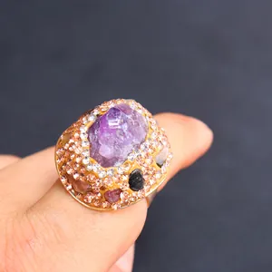Detailaufnahme eines Goldrings mit Rohamethyst und Pavé-besetzten Strasssteinen
