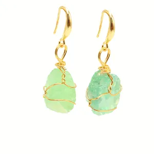 Macro detail of natural light green crystal raw stone earrings with gold wire wrap technique