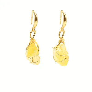 Detailed close-up of handmade gold wire-wrapped earrings with raw yellow crystal stones