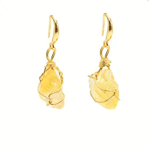 Detailed macro view of yellow natural crystal wire wrapped drop earrings with gold finish